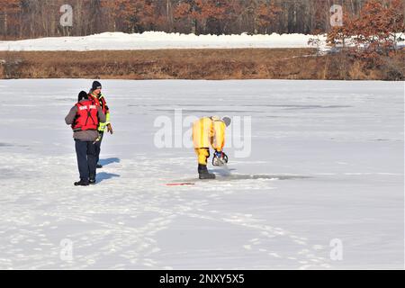 Feuerwehrleute mit dem Tauchteam der Feuerwehr üben ein Eisrettungsszenario am 11. Januar 2023 an einem gefrorenen Big Sandy Lake auf der South Post in Fort McCoy, Wisconsin. Mehrere Feuerwehrleute aus dem Team zogen einen Anzug an, schnallten sich einen Lufttank und eine Vollmaske an und tauchten in die Tiefen des Big Sandy Lake unter dem Eis an der South Post von Fort McCoy. Die Taucher bearbeiteten Tiefen von bis zu 15 Fuß oder mehr, um verschiedene Arten von Rettungsszenarien unter der Anleitung von anderen Feuerwehrleuten durchzuführen. Taucher wechselten sich ab und gingen in und aus dem gleichen Loch, das ich geschnitten hatte Stockfoto