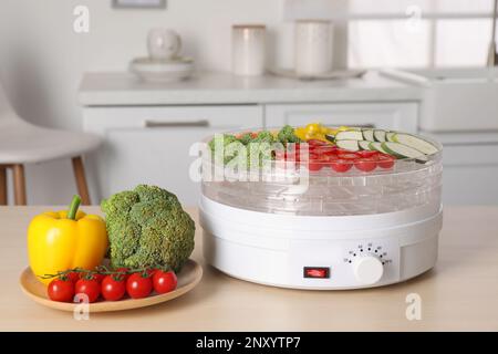 Gemüse- und Fruchttrocknermaschine auf Holztisch in der Küche Stockfoto