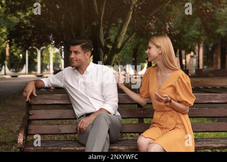 Ein Mann hat ein langweiliges Date mit einer gesprächigen Frau auf der Bank im Park Stockfoto