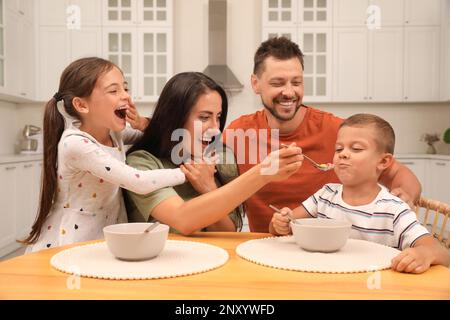 Glückliche Familie mit Kindern, die Spaß beim Frühstück zu Hause haben Stockfoto