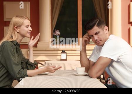 Ein Mann hat ein langweiliges Date mit einer gesprächigen Frau im Café draußen Stockfoto