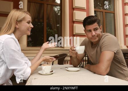 Ein Mann hat ein langweiliges Date mit einer gesprächigen Frau im Café draußen Stockfoto