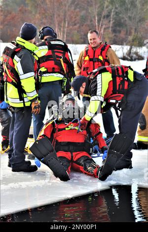 Feuerwehrleute mit dem Tauchteam der Feuerwehr üben ein Eisrettungsszenario am 11. Januar 2023 an einem gefrorenen Big Sandy Lake auf der South Post in Fort McCoy, Wisconsin. Mehrere Feuerwehrleute aus dem Team zogen einen Anzug an, schnallten sich einen Lufttank und eine Vollmaske an und tauchten in die Tiefen des Big Sandy Lake unter dem Eis an der South Post von Fort McCoy. Die Taucher bearbeiteten Tiefen von bis zu 15 Fuß oder mehr, um verschiedene Arten von Rettungsszenarien unter der Anleitung von anderen Feuerwehrleuten durchzuführen. Taucher wechselten sich ab und gingen in und aus dem gleichen Loch, das ich geschnitten hatte Stockfoto