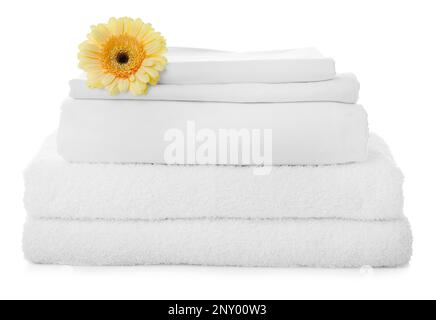 Ein Stapel Handtücher und Bettlaken mit Gerbera auf weißem Hintergrund Stockfoto