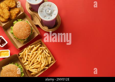 Flach liegend mit köstlichem Fast-Food-Menü auf rotem Hintergrund. Platz für Text Stockfoto