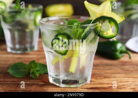 Würziger Cocktail mit Jalapeno, Karambola und Minze auf Holztisch, Nahaufnahme Stockfoto