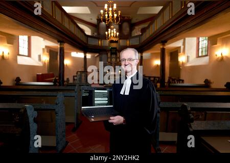 Wiesbaden, Deutschland. 24. Februar 2023. Thomas Hartmann, Pastor der protestantischen Gemeinde Thalkirche, steht mit seinem Computer im historischen Thalkirche. Der Pastor predigt mit ChatGPT (Generative Pre-trained Transformer), einem Chatbot. Ein Chatbot, kurz bot, ist ein textbasiertes Dialogsystem, das das Chatten mit einem technischen System ermöglicht. (An dpa 'Pastor aus Wiesbaden hat Predigten mit ChatGPT geschrieben') Kredit: Andreas Arnold/dpa/Alamy Live News Stockfoto