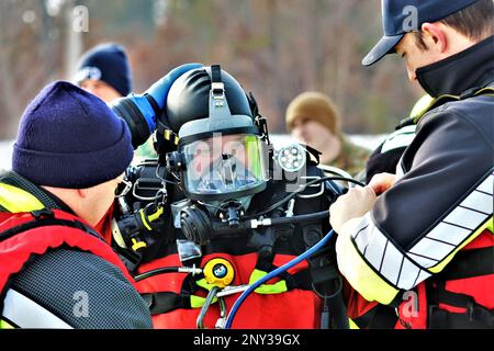 Feuerwehrleute mit dem Tauchteam der Feuerwehr üben ein Eisrettungsszenario am 11. Januar 2023 an einem gefrorenen Big Sandy Lake auf der South Post in Fort McCoy, Wisconsin. Mehrere Feuerwehrleute aus dem Team zogen einen Anzug an, schnallten sich einen Lufttank und eine Vollmaske an und tauchten in die Tiefen des Big Sandy Lake unter dem Eis an der South Post von Fort McCoy. Die Taucher bearbeiteten Tiefen von bis zu 15 Fuß oder mehr, um verschiedene Arten von Rettungsszenarien unter der Anleitung von anderen Feuerwehrleuten durchzuführen. Taucher wechselten sich ab und gingen in und aus dem gleichen Loch, das ich geschnitten hatte Stockfoto