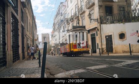 Portugal, Lissabon - 17. Juli 2022: Straßenbahnen, die durch die engen Gassen der europäischen Stadt fahren. Aktion. Straßenbahnen, die durch die europäischen Straßen der Altstadt fahren. Stockfoto