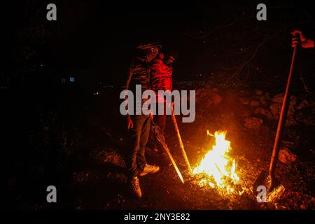 Nablus, Palästina. 01. März 2023. Maskierte Palästinenser, die nachts Holzstöcke um den Feuerstand trugen, bewacht, um Angriffe der jüdischen Siedler südlich von Nablus im Westjordanland abzuwehren. Die Angriffe von Siedlern auf Palästinenser, insbesondere auf Dörfer südlich von Nablus, wie Hawara Burin, nahmen zu. Der letzte davon war in der Stadt Hawara, deren Schaden dem Abbrennen von Dutzenden von Häusern und Geschäften und mehr als hundert Autos gleichkam. Der palästinensische Ministerpräsident Muhammad Shtayyeh erklärte, dass die Gesamtverluste auf fast $5 Millionen Euro geschätzt würden. Kredit: SOPA Images Limited/Alamy Live News Stockfoto