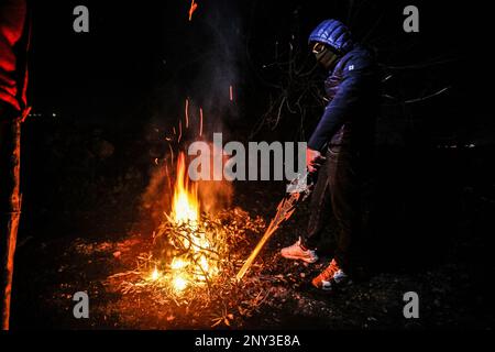 Nablus, Palästina. 01. März 2023. Maskierte Palästinenser, die nachts Holzstöcke um den Feuerstand trugen, bewacht, um Angriffe der jüdischen Siedler südlich von Nablus im Westjordanland abzuwehren. Die Angriffe von Siedlern auf Palästinenser, insbesondere auf Dörfer südlich von Nablus, wie Hawara Burin, nahmen zu. Der letzte davon war in der Stadt Hawara, deren Schaden dem Abbrennen von Dutzenden von Häusern und Geschäften und mehr als hundert Autos gleichkam. Der palästinensische Ministerpräsident Muhammad Shtayyeh erklärte, dass die Gesamtverluste auf fast $5 Millionen Euro geschätzt würden. Kredit: SOPA Images Limited/Alamy Live News Stockfoto