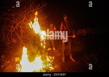 Nablus, Palästina. 01. März 2023. Maskierte Palästinenser, die nachts Holzstöcke um den Feuerstand trugen, bewacht, um Angriffe der jüdischen Siedler südlich von Nablus im Westjordanland abzuwehren. Die Angriffe von Siedlern auf Palästinenser, insbesondere auf Dörfer südlich von Nablus, wie Hawara Burin, nahmen zu. Der letzte davon war in der Stadt Hawara, deren Schaden dem Abbrennen von Dutzenden von Häusern und Geschäften und mehr als hundert Autos gleichkam. Der palästinensische Ministerpräsident Muhammad Shtayyeh erklärte, dass die Gesamtverluste auf fast $5 Millionen Euro geschätzt würden. Kredit: SOPA Images Limited/Alamy Live News Stockfoto