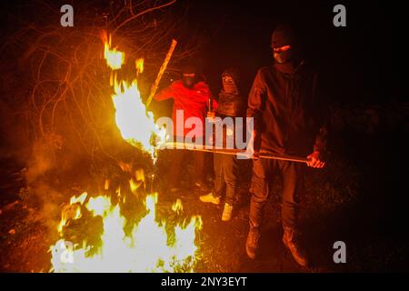 Maskierte Palästinenser, die nachts Holzstöcke um den Feuerstand trugen, bewacht, um Angriffe der jüdischen Siedler südlich von Nablus im Westjordanland abzuwehren. Die Angriffe von Siedlern auf Palästinenser, insbesondere auf Dörfer südlich von Nablus, wie Hawara Burin, nahmen zu. Der letzte davon war in der Stadt Hawara, deren Schaden dem Abbrennen von Dutzenden von Häusern und Geschäften und mehr als hundert Autos gleichkam. Der palästinensische Ministerpräsident Muhammad Shtayyeh erklärte, dass die Gesamtverluste auf fast $5 Millionen Euro geschätzt würden. (Foto: Nasser Ishtayeh/SOPA Images/Sipa USA) Stockfoto