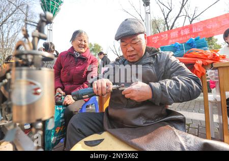 HUZHOU, CHINA - 2. MÄRZ 2023 - Ein Freiwilliger reparierte Schuhe kostenlos in Wuyang Community, Wuyang Street, Deqing County, Huzhou City, Ostchina Zhejia Stockfoto