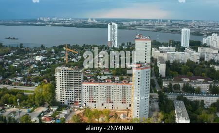 Draufsicht der Baustelle des Hauses im Hintergrund der Stadt mit Fluss. Aktie-Aufnahmen. Bau eines Wohngebäudes im Hintergrund des Horizonts Stockfoto