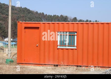 Leuchtend orangefarbener Transportbehälter auf der Baustelle Stockfoto