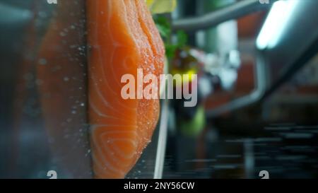 Nahaufnahme von gesalzenem rotem Fisch. Clip. Filets mit frischem Rotfisch werden vor dem Kochen gesalzen. Vertikales Filmmaterial mit kulinarischer Zubereitung von Fischgerichten. Stockfoto