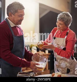 Kochen ist Liebe, die essbar ist. Ein Seniorenpaar, das in der Küche backt. Stockfoto
