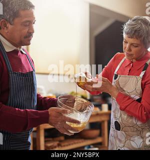 Paare, die zusammen kochen, bleiben zusammen. Ein Seniorenpaar, das in der Küche backt. Stockfoto