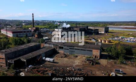 Städtische Industrie von der Drohne. Aktion. Ein Blick von der Höhe bis zum Stadtrand mit hohen Schornsteinen, aus denen Rauch austritt. Hochwertige 4K-Aufnahmen Stockfoto