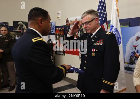 Brigg. Gen. Daryl O. Hood (links), kommandierender General des 20. Kommandos für chemische, biologische, radiologische, nukleare und explosive Stoffe (CBRNE), Überreicht Major William J. Cook III (rechts) während seiner Ruhestandszeremonie auf dem Aberdeen Proving Ground, Maryland, 21. Februar die amerikanische Flagge. Cook schloss seine 20-jährige Karriere als Kommandorichter Advocate am CBRNE-Kommando 20. ab. USA Armeefoto von Angel D. Martinez-Navedo. Stockfoto