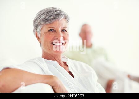Elegante Frau, die mit einem Mann lächelt. Porträt einer eleganten, reifen Frau, die mit einem Mann im Hintergrund lächelt. Stockfoto