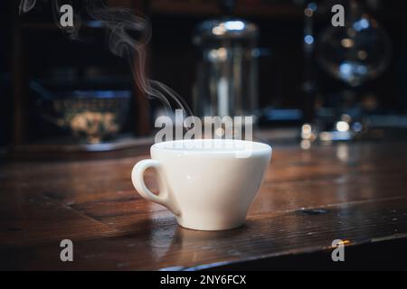 Heiße Kaffeetasse auf dem Holztisch im unscharfen Hintergrund des Coffee Shops. Stockfoto