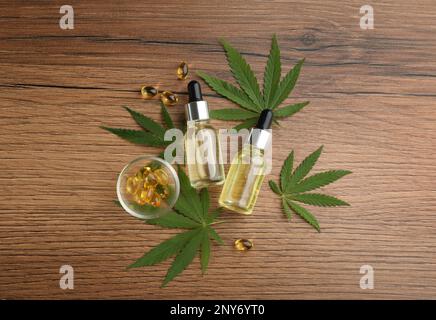 Zusammensetzung mit CBD-Öl, THC-Tinktur und Hanfblättern auf Holztisch, flach liegend Stockfoto