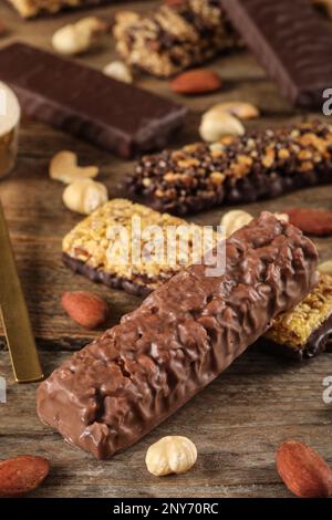 Verschiedene leckere Proteinriegel und Nüsse auf Holztisch Stockfoto