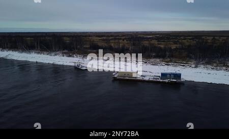 Luftaufnahme eines Kutschers auf einem Winterfluss mit Eis. Konzept des Wassertransports von Gütern Stockfoto