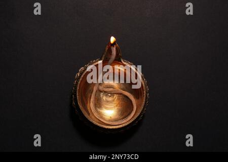 Beleuchtete Diya auf dunklem Hintergrund, Draufsicht. Diwali-Lampe Stockfoto