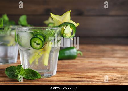 Würziger Cocktail mit Jalapeno, Karambola und Minze auf einem Holztisch. Platz für Text Stockfoto