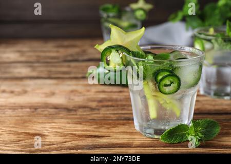 Würziger Cocktail mit Jalapeno, Karambola und Minze auf einem Holztisch. Platz für Text Stockfoto