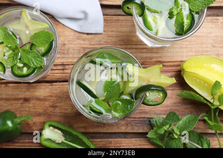 Gläser scharfer Cocktails mit Jalapeno, Karambola und Minze auf einem Holztisch, flach liegend Stockfoto