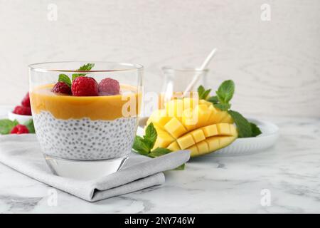 Köstlicher Chia-Pudding mit Mangosauce und Himbeeren auf einem weißen Marmortisch Stockfoto