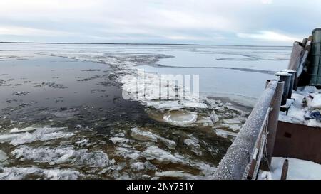 Luftaufnahme eines Kutschers auf einem Winterfluss mit Eis. Konzept des Wassertransports von Gütern Stockfoto