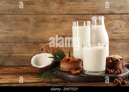 Verschiedene vegane Milch und Zutaten auf Holztisch. Platz für Text Stockfoto