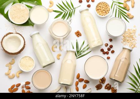 Verschiedene vegane Milch und Zutaten auf weißem Hintergrund, flach liegend Stockfoto