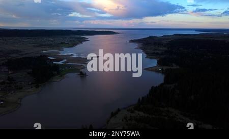 Luftaufnahme eines sumpfigen Geländes im Hintergrund des Sonnenuntergangs am Himmel. Clip. Fluss und Felder biegen Stockfoto