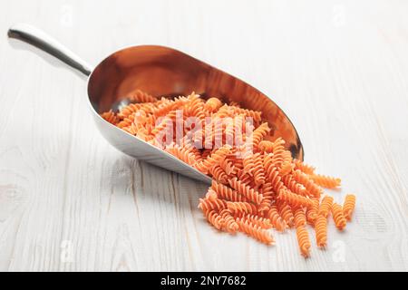 Rote Linsenfusilli-Pasta auf Holzhintergrund. Mit roher Pasta und roten Linsen füllen. Glutenfreie Nudeln. Stockfoto