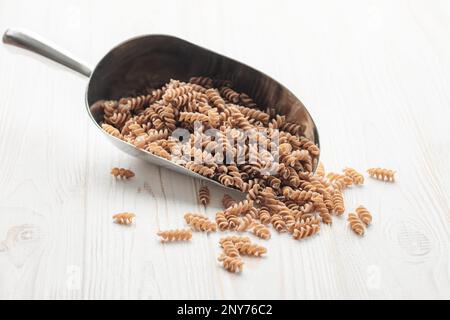 Grüne Linsenfusilli-Pasta auf Holzhintergrund. Eine Portion rohe Pasta und grüne Linsen. Glutenfreie Pasta. Stockfoto