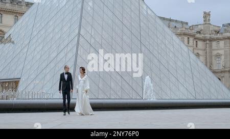 Hochzeitspaar, das vor dem Hintergrund der Louvre-Pyramide spaziert, Frankreich, Paris. Aktion. Romantische Hochzeit in der Nähe des Museums Stockfoto