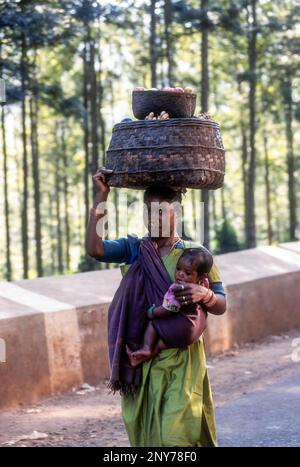 Stammesfrau trägt ihre Tochter auf der Hüfte und trägt einen Gemüsekorb auf dem Kopf im Araku-Tal bei Vishakapatnam, Vizag, Andhra Pradesh, Indien Stockfoto