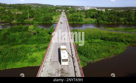 Luftaufnahme von oben auf eine kleine Straßenbrücke über den Fluss in ländlicher Gegend. Clip. Autos auf der Brücke und grüne Vegetation Stockfoto