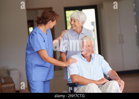 Die Hölle wird in kürzester Zeit auf seinen Füßen sein. Eine Krankenschwester, die ihrem älteren Patienten und seiner Frau gute Nachrichten überbringt. Stockfoto