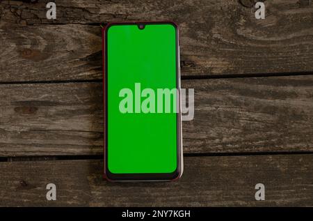 Ein Telefon mit grünem Bildschirm liegt auf einer Tafel Stockfoto