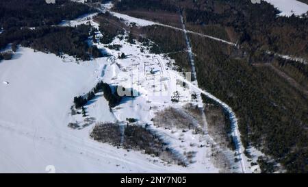 Winterlandschaft aus der Luft mit schneebedeckten Feldern und wachsenden Kiefern. Clip. Cottages und kleine Häuser umgeben von Schneeswüste Stockfoto