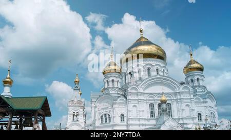 Luftaufnahme Einer weißen Kirche mit goldenen Kuppeln. Clip. Große, wunderschöne orthodoxe Kirche auf einem wolkigen Himmelshintergrund Stockfoto