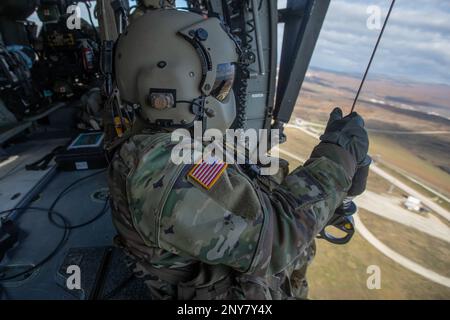 Sgt. 1. Klasse Jonas Chinea, ein Kosovo Force (KFOR) Regional Command-East (RC-E) Soldat mit der medizinischen Evakuierungseinheit der Charlie Company zugewiesen, 2. Bataillon, 149. Luftfahrtregiment, wartet auf seine Position, um eine Hebeoperation von einem UH-60 Black Hawk Helikopter in Camp Bondsteel, Kosovo am 6. Januar durchzuführen, 2023. Stockfoto