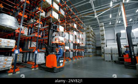 Serbien - Belgrad, 20. September 2022: Innenbereich eines großen Fabriklagers mit Arbeitern in Uniform in Ladern. Kreativ. Viele Pakete in Regalen, Stockfoto